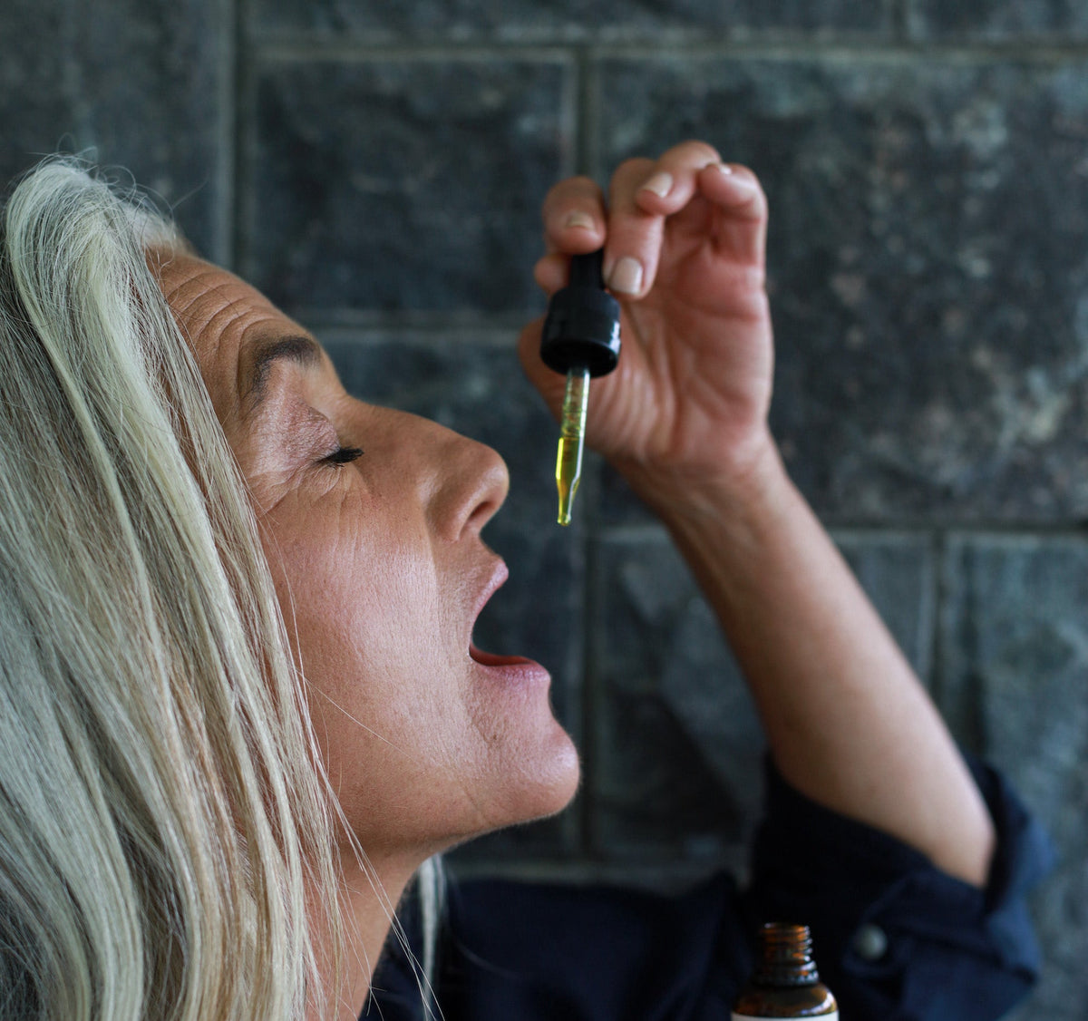 A woman taking recovery tincture.