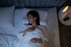 Woman relaxing in bed using Dragon Hemp melatonin-free sleep tincture.