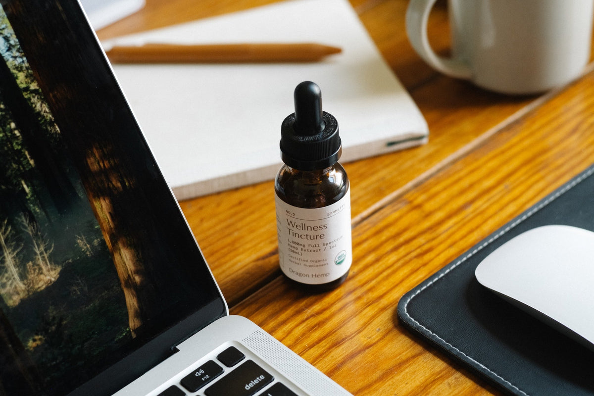 Dragon Hemp Wellness Tincture for daily focus and brain clarity, photographed on a wooden apothecary desk